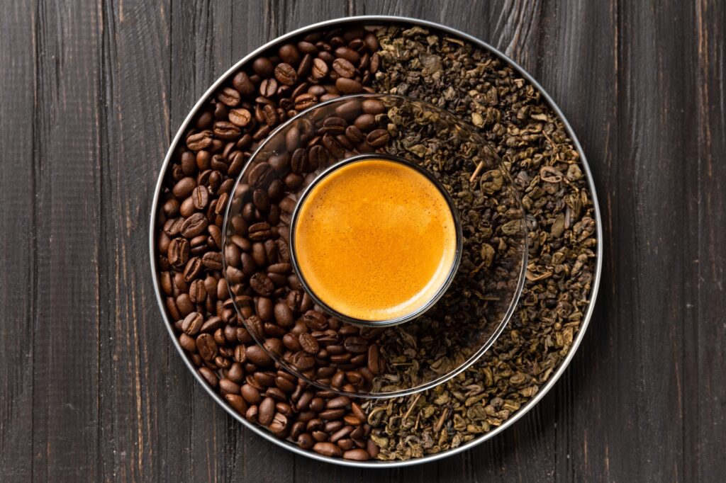 Composition of green tea, coffee beans and coffee in a cup on a dark background top view.